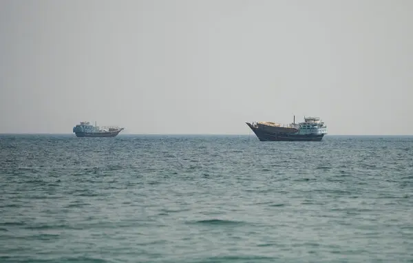 Cargo ships transit a strategic sea lane as US-Iran tensions raise risks to global trade and energy supplies.