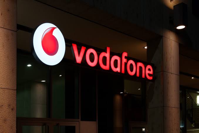 Vodafone branding alongside telecom-themed visuals representing E&'s multibillion-dollar stake sale to Xavier Niel.