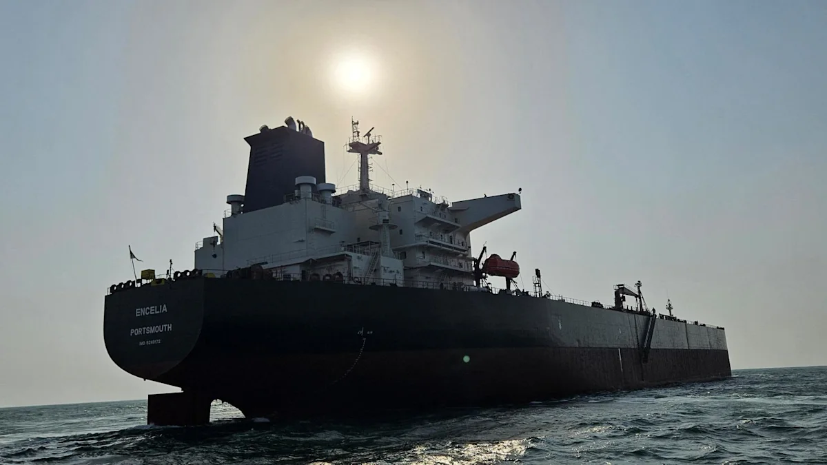 US Navy vessel in the Strait of Hormuz alongside a disabled commercial tanker, July 2026, with smoke visible from the engine room